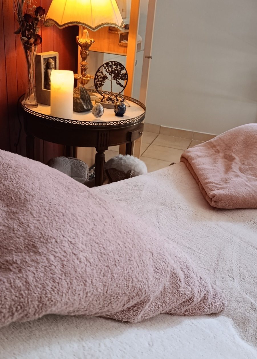 Espace de soins cocooning Table de soins avec des couleurs chaleureuses, un oreiller et une couverture. Eclairage doux avec une lampe et une bougie
